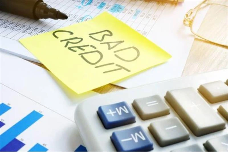 Note reading “bad credit” beside a calculator and financial documents