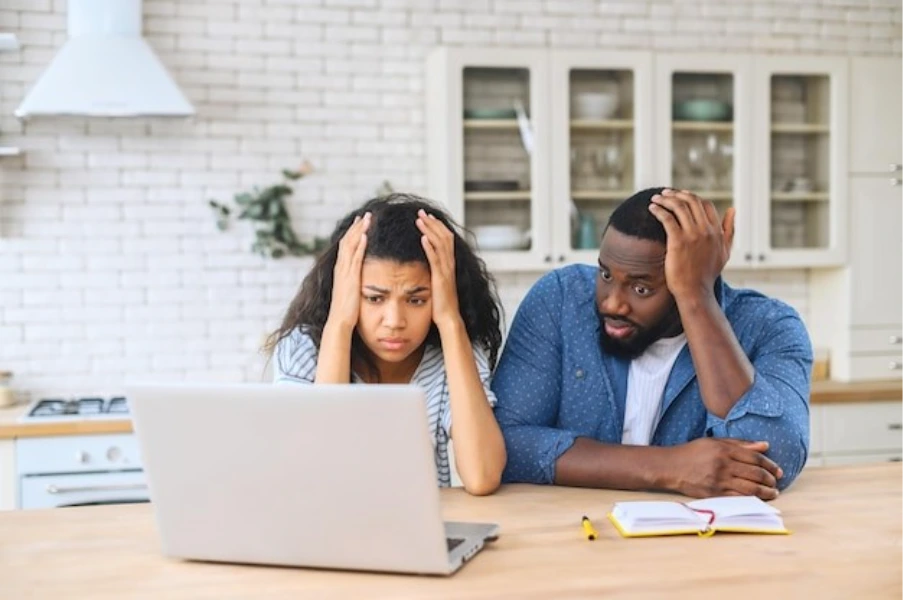 couple looking worried while reviewing mortgage costs on laptop at home